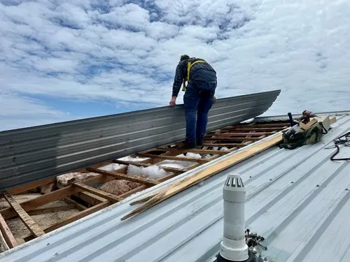 Roof repair contractor in Willmar, MN performing full exterior assessment while employee works on residential roof replacement